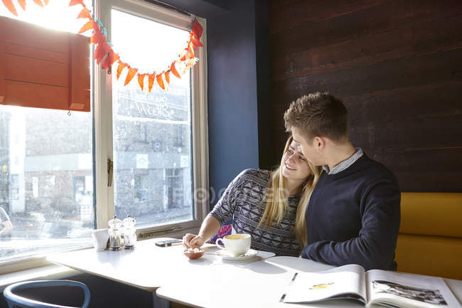 Romantica giovane coppia in data nel sedile del finestrino del caffè — Foto stock