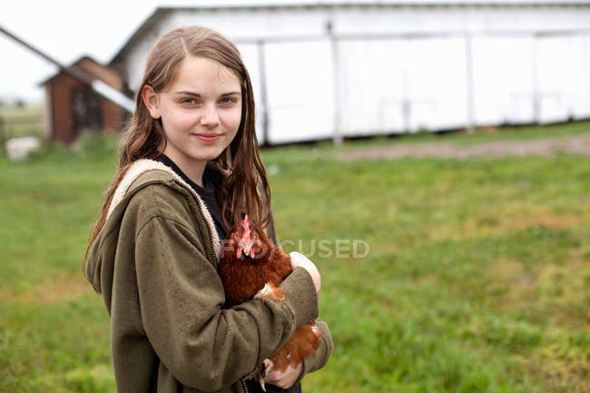 Девушка, несущая курицу на ферме — стоковое фото