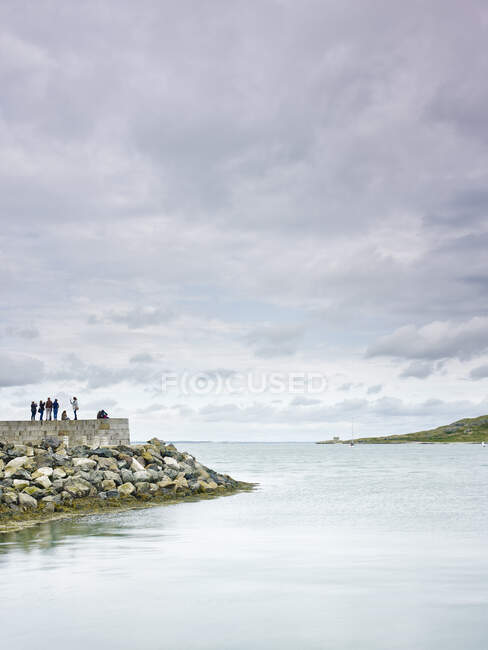 Groupe de personnes debout sur le mur du port, Howth, Dublin Bay, République d'Irlande — Photo de stock
