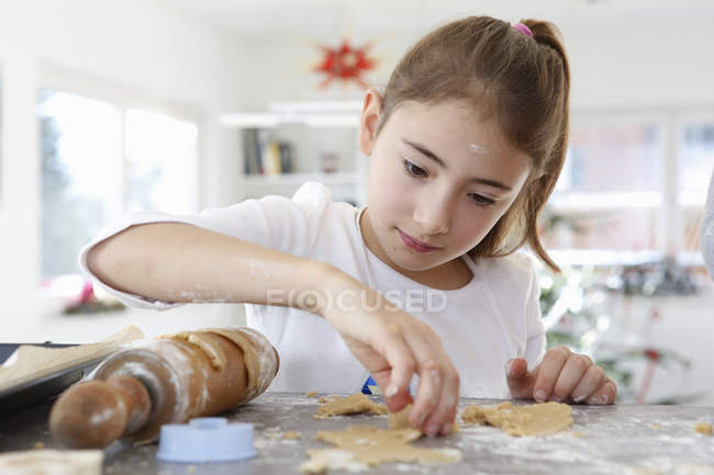 Mädchen schaut nach unten und rollt Teig-Keksteig aus — Stockfoto
