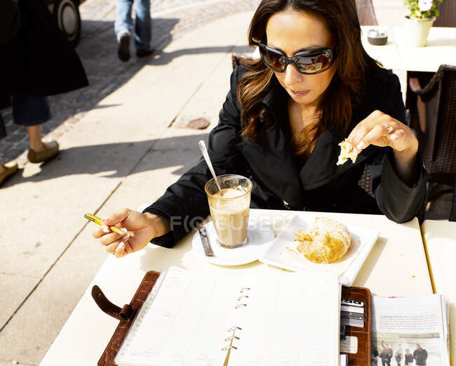 Mujer comiendo en un restaurante al aire libre - foto de stock