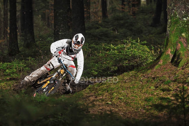 Mountain biker riding muddy forest track — Stock Photo