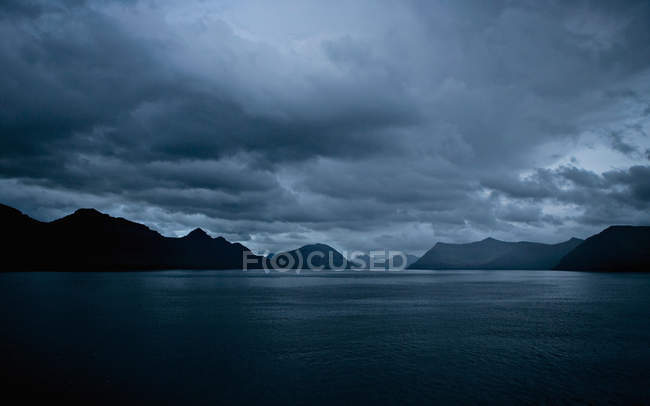Cielo tormentoso sobre un lago tranquilo - foto de stock