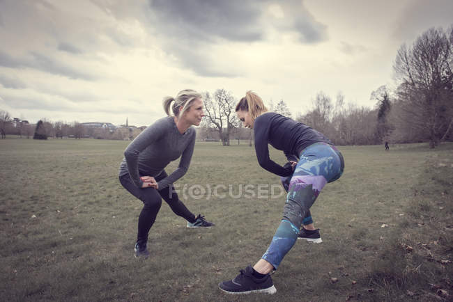 Women in field in lunge pose stretching — Stock Photo