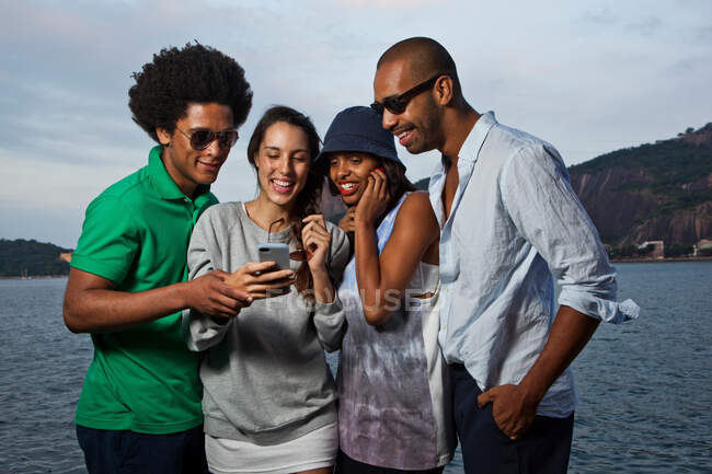 Четверо друзей смотрят на мобильный телефон — стоковое фото