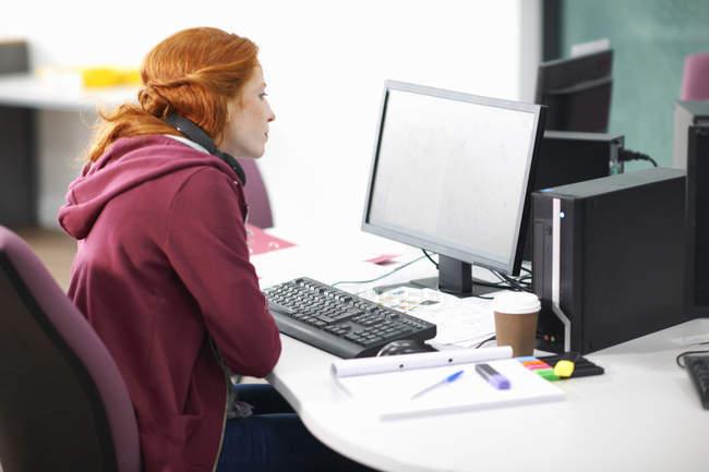 Junge Studentin am Schreibtisch liest Computer — Stockfoto