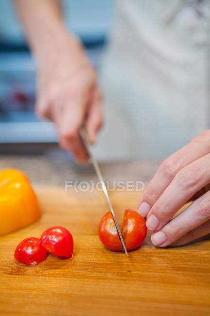Donna affettare pomodorini ciliegia — Foto stock