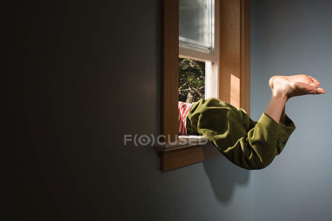 Legs of boy climbing out of window — Stock Photo