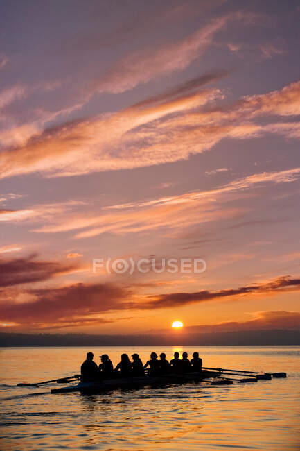 Oito pessoas remando ao pôr do sol — Fotografia de Stock