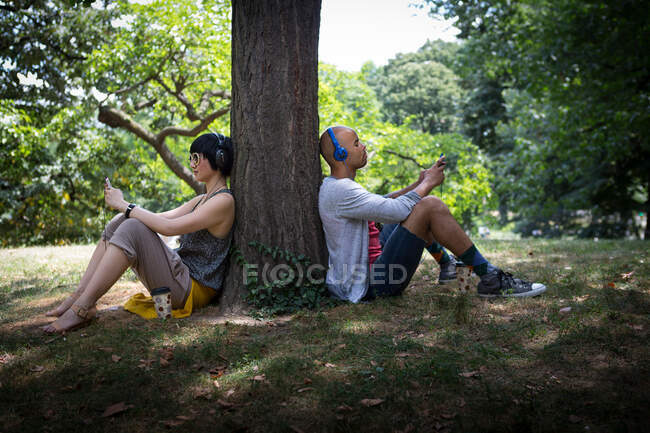 Casal jovem encostado ao tronco da árvore — Fotografia de Stock
