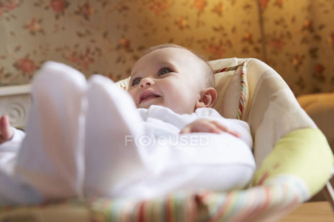 Baby girl lying on baby bouncer chair in nursery — Stock Photo