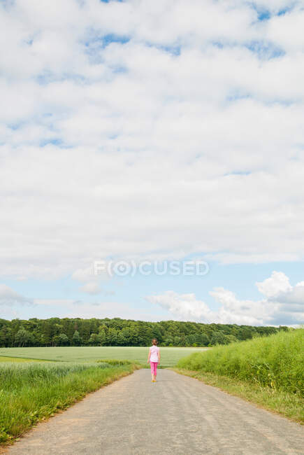 Menina andando estrada país abaixo — Fotografia de Stock