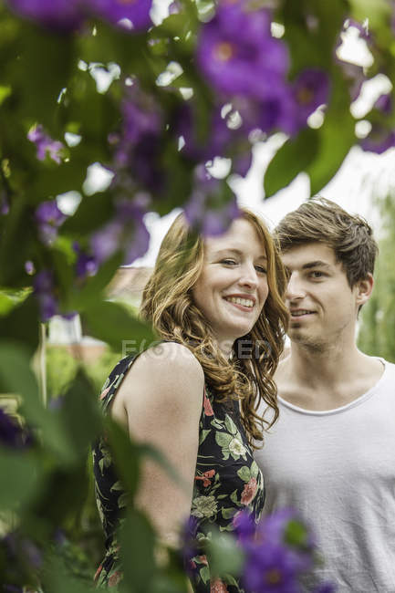 Portrait of young couple surrounded by foliage and flowers — Stock Photo