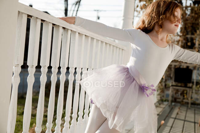 Девушка танцует в балетном костюме на крыльце — стоковое фото