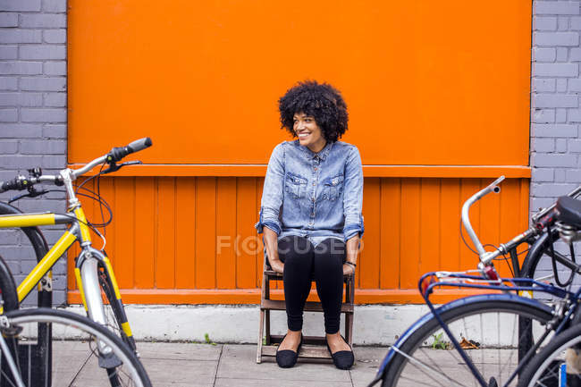 Портрет зрелой женщины, сидящей перед оранжевой стеной — стоковое фото