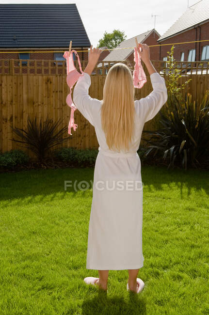Woman putting lingerie in washing line — Stock Photo