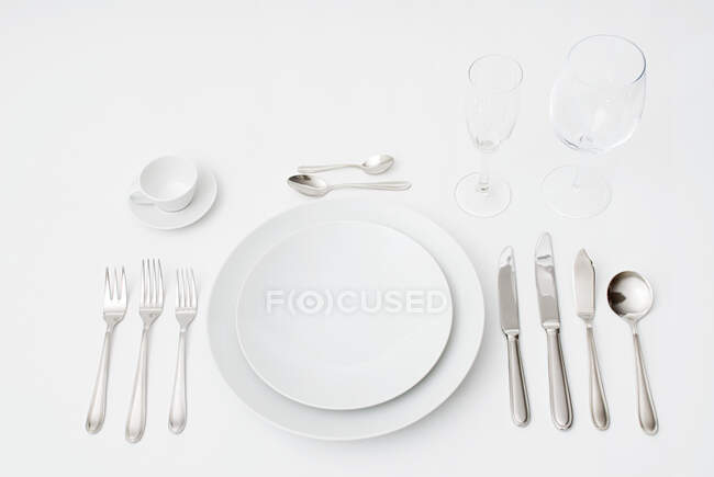 Formal eating place setting with cutlery, plates and drinking glasses on white background — Stock Photo