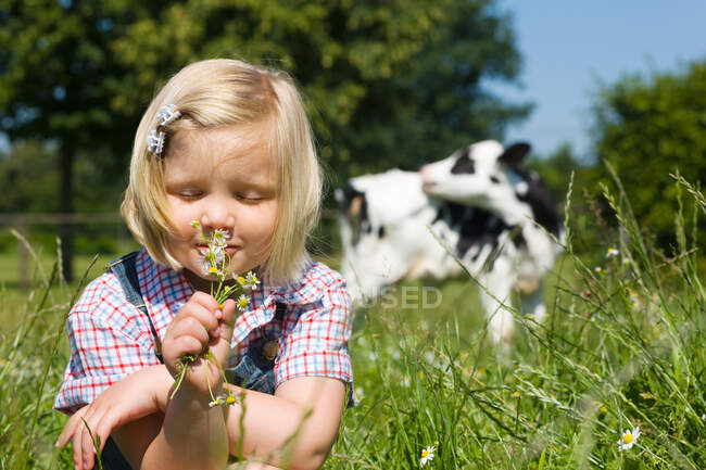 Uma rapariga a cheirar flores silvestres — Fotografia de Stock