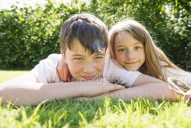 Retrato de hermano y hermana acostados sobre hierba - foto de stock