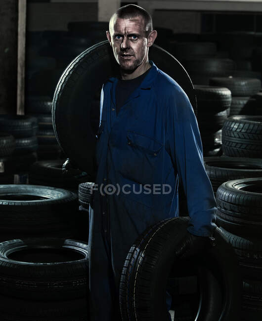 Car mechanic in workshop with car tires — Stock Photo