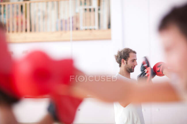 Junger Mann und Trainer boxen im Fitnessstudio — Stockfoto