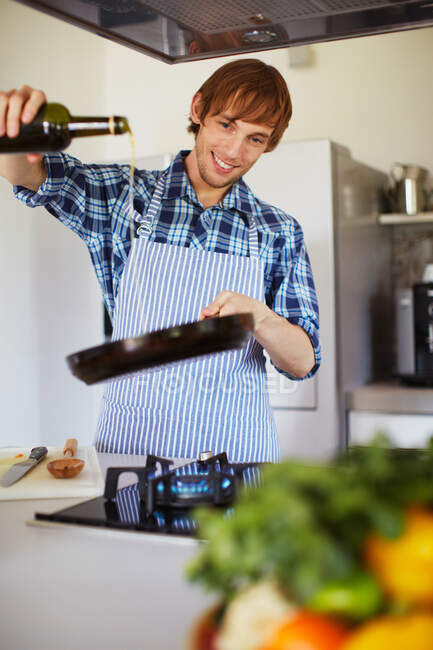 Uomo cucina con vino in cucina — Foto stock