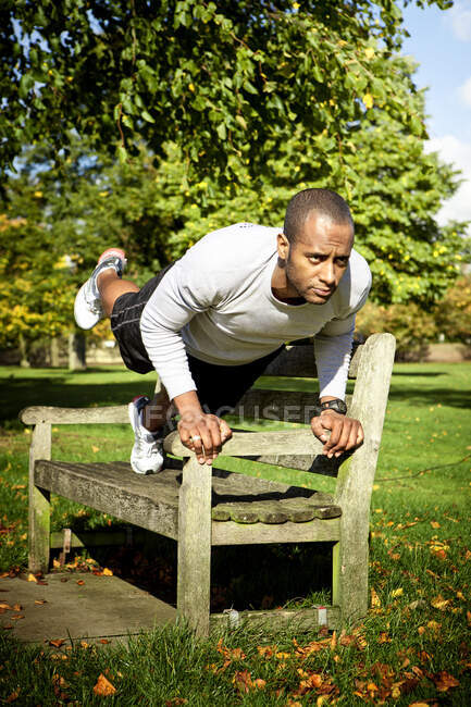 Man in plank position on park bench — Stock Photo