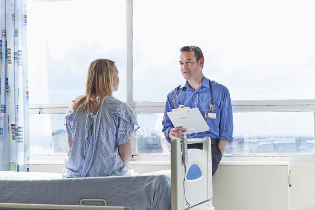 Doctor talking to patient sitting on hospital bed — Stock Photo