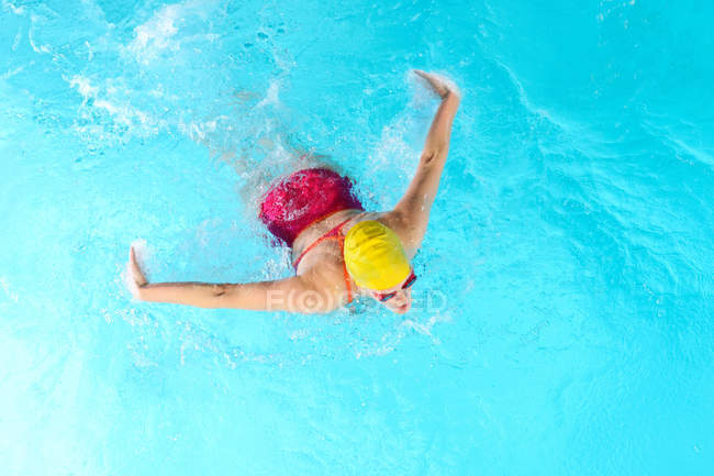 Mulher madura fazendo borboleta acidente vascular cerebral na piscina — Fotografia de Stock