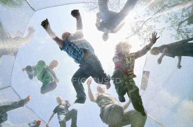 Hommes et garçons mûrs sautant sur le trampoline, vue à faible angle — Photo de stock