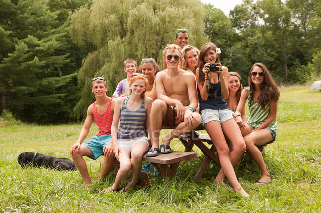 Adolescentes relaxando juntos, sentados em uma mesa de piquenique no campo — Fotografia de Stock