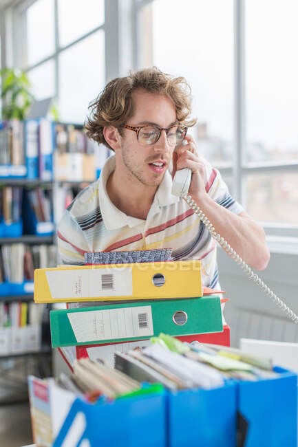 Young man using telephone in creative office — Stock Photo