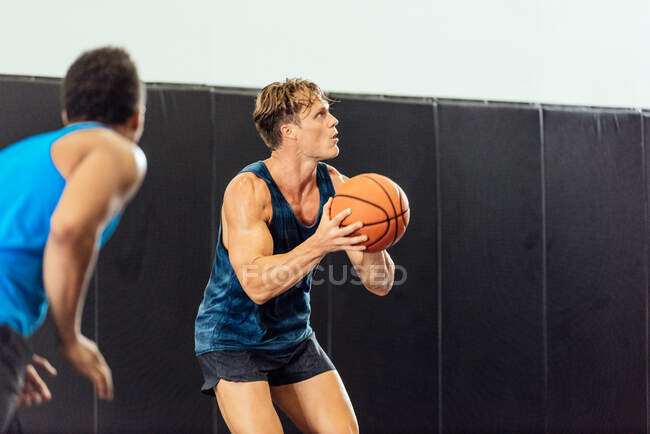 Male basketball player poised with ball in basketball game — Stock Photo