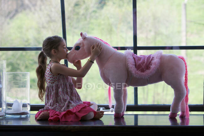Chica con caballo de juguete - foto de stock