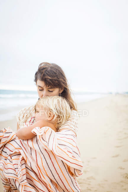 Madre abrazando niño envuelto en toalla - foto de stock
