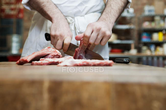 Açougueiro que prepara costelas de porco — Fotografia de Stock