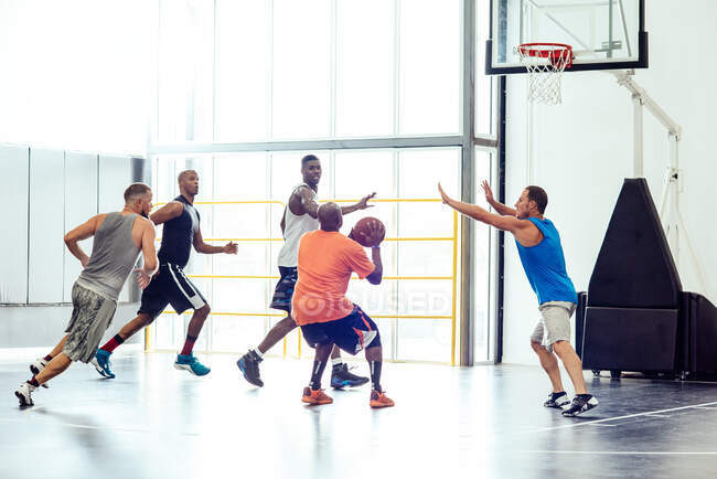 Jogador de basquete masculino apontando bola para aro no jogo de basquete — Fotografia de Stock