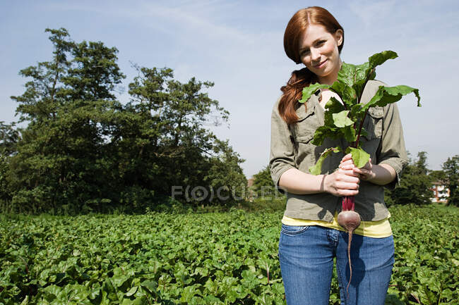 Young woman holding fresh beetroot in field — Stock Photo