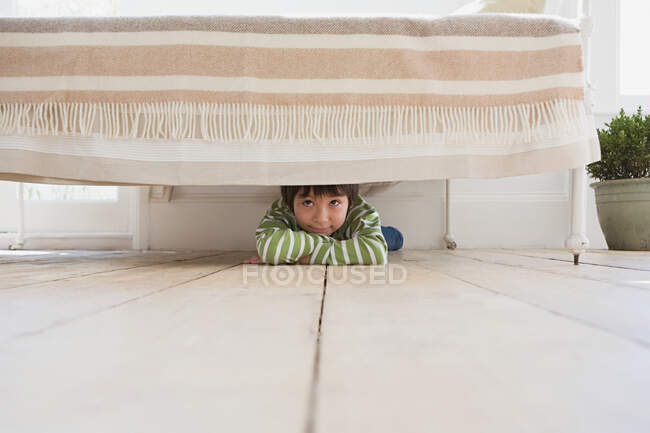 Ragazzo nascosto sotto un letto — Foto stock