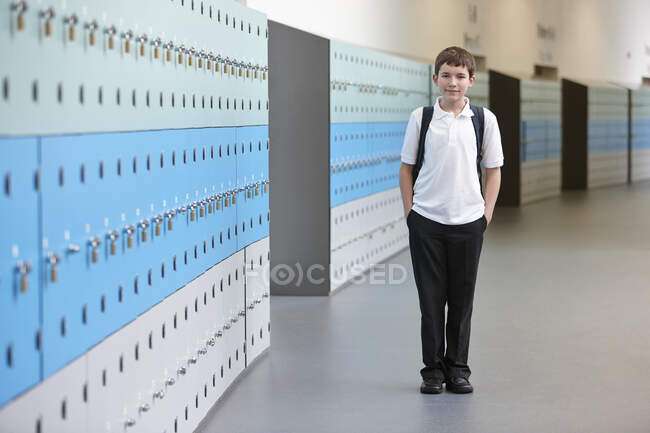 Portrait of schoolboy with hands in pockets in school corridor — Stock Photo