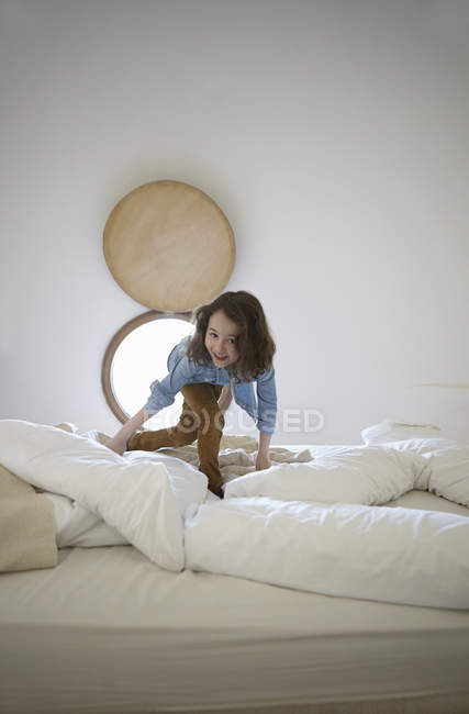 Freimütiges Porträt eines Mädchens, das auf dem Bett spielt — Stockfoto