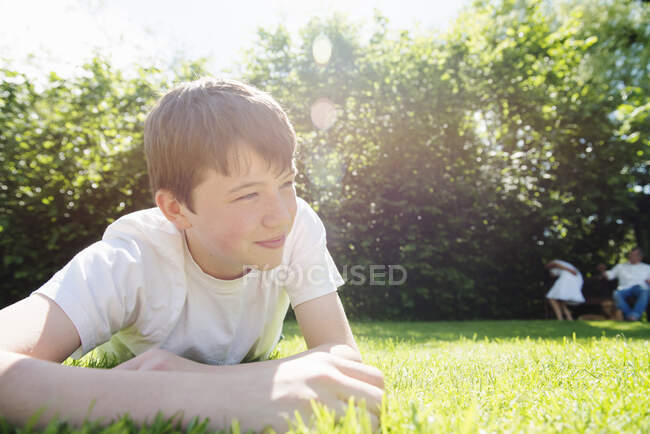 Retrato de adolescente deitado na grama, olhando para longe — Fotografia de Stock