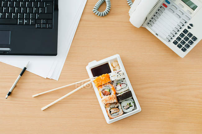 Sushi rolls and chopsticks at desk — Stock Photo