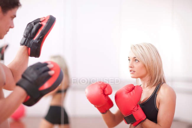 Young woman wearing boxing gloves in gym — Stock Photo