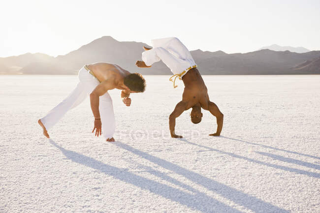Two men on Bonneville Salt Flats performing capoeira, Utah, USA — Stock Photo