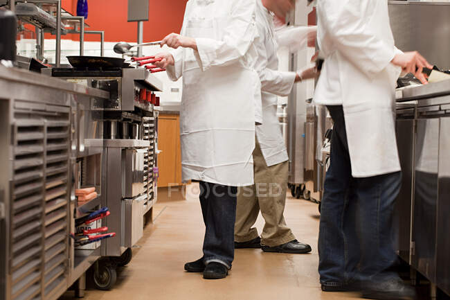 Chefs preparando comida en cocina comercial - foto de stock