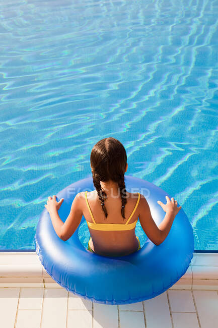 Menina com anel inflável pela piscina — Fotografia de Stock