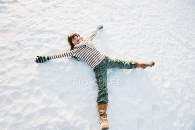 Girl making snow angel — Stock Photo