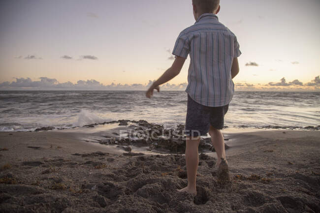 Niño con mochila en la playa - foto de stock