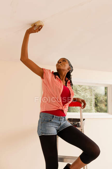 Woman priming wall in new home — Stock Photo